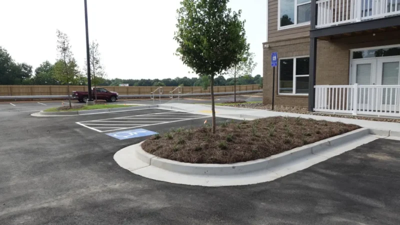 Photo of a parking lot that has been redone as well as a fresh sidewalk and curbing at an apartment complex.