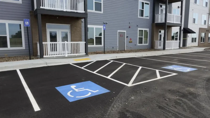 Fresh striping and handicap markings on a parking lot surface with an apartment building in the back.