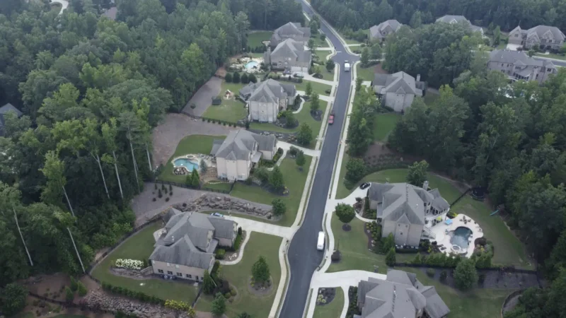 Aerial view of a neighborhood where the streets were milled and repaved. You can see the fresh, smooth blacktop in the photo, as well as multiple houses surrounded by forest.