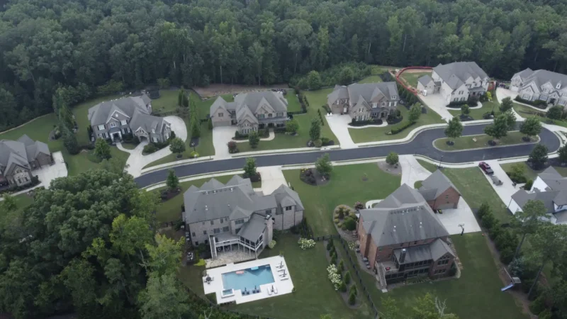 Aerial view of a neighborhood where the streets were milled and repaved. You can see the fresh, smooth blacktop in the photo, as well as multiple houses surrounded by a forest.