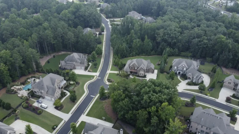 Aerial view of a neighborhood where the streets were milled and repaved. You can see the fresh, smooth blacktop in the photo, as well as multiple houses surrounded by forest.