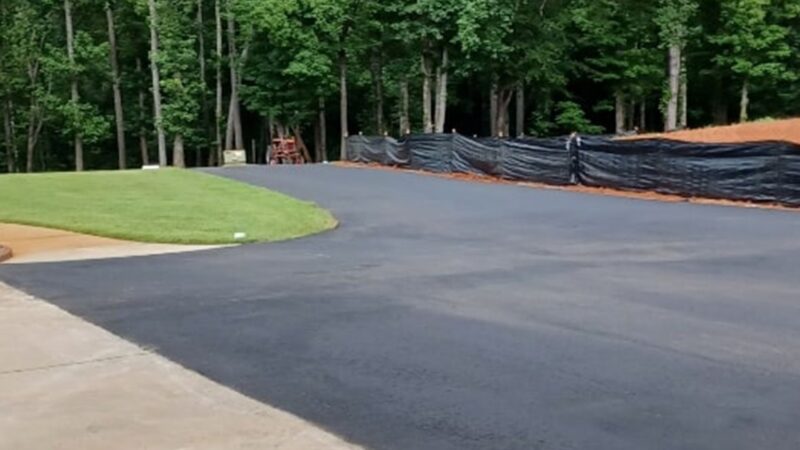 A long and windy asphalt driveway that as been repaved with asphalt.