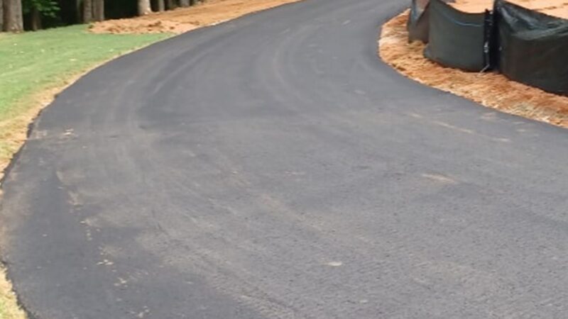 A long and windy asphalt driveway that as been repaved with asphalt.