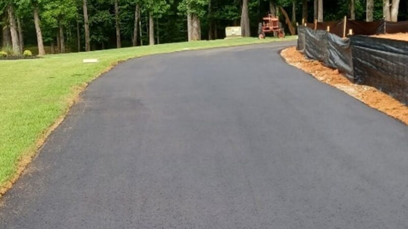 A long and windy asphalt driveway that as been repaved with asphalt.