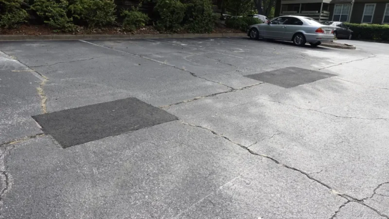 Two crack and pothole patch repairs in a parking lot.