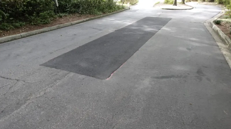 Photo of a crack and pothole repair on a road leading into a condo complex.