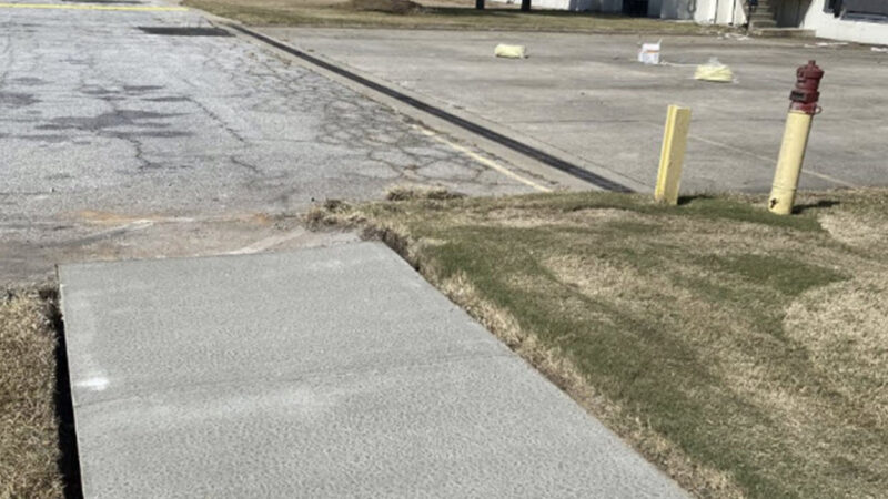 Photo of a sidewalk that has been freshly replaced leading to a parking lot.