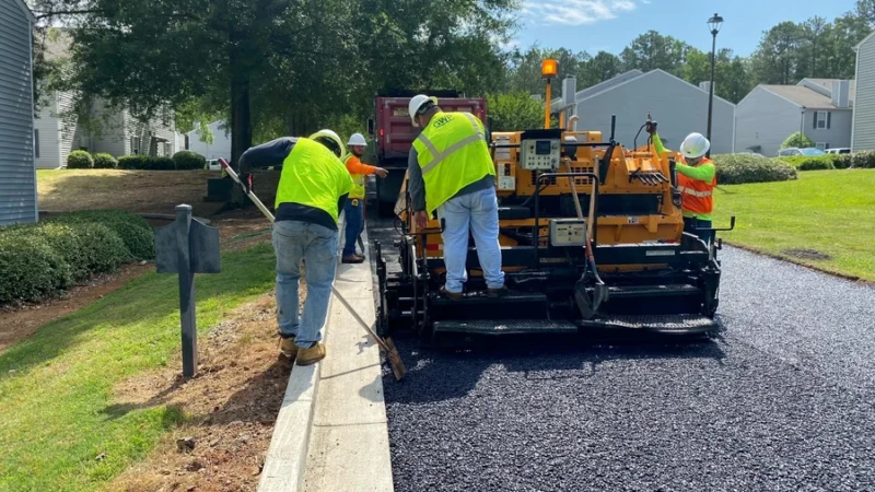 GWP workers are using a machine and tools to pave a road.